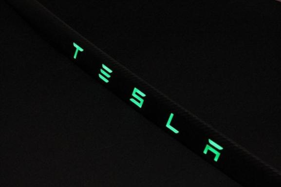 Carbon rear trunk trim with LEDs for Tesla Model S from Custom Class, made of genuine carbon fiber with a grey gloss UV-resistant coating.