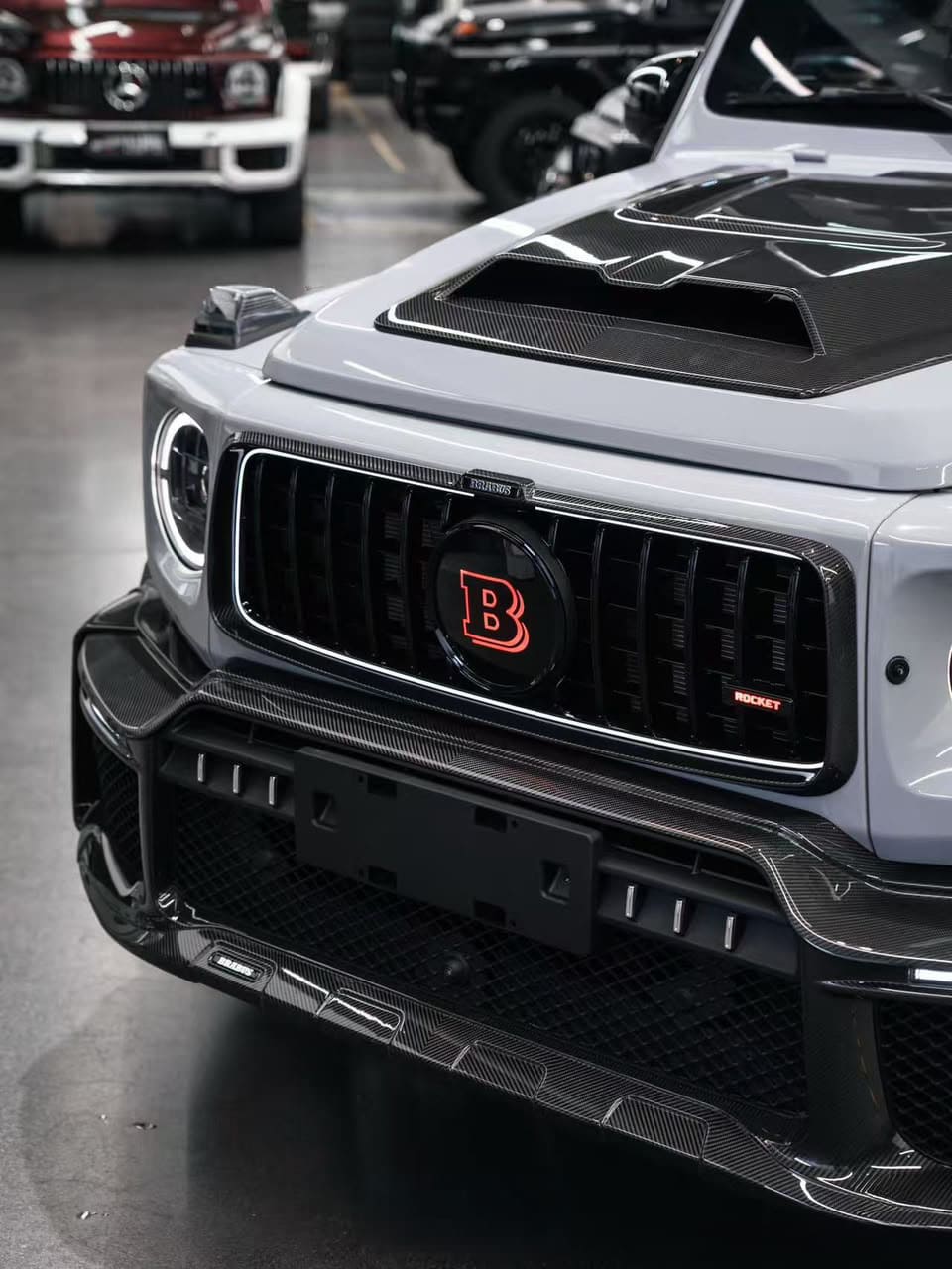Front view of Mercedes-Benz G-Class W465 featuring a carbon fiber front grille with an illuminated red "B" emblem and Rocket badge.